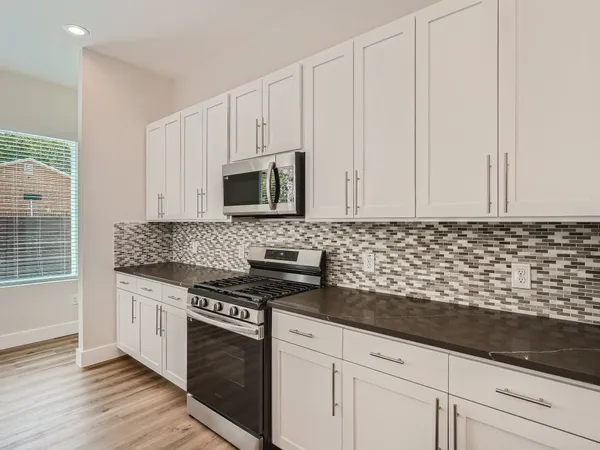 a kitchen with granite countertop white cabinets and stainless steel appliances