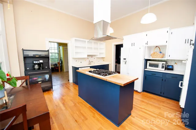 a kitchen with stainless steel appliances a stove top oven a sink refrigerator and a dining table with wooden floor