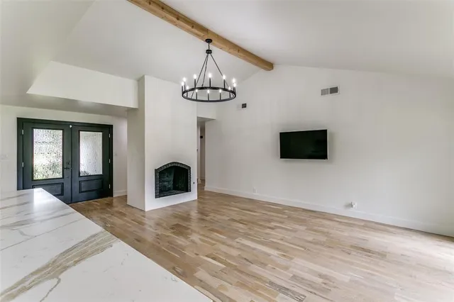 a view of a livingroom with a fireplace a chandelier and wooden floor