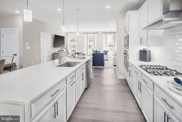 a large white kitchen with lots of counter space a sink appliances and cabinets