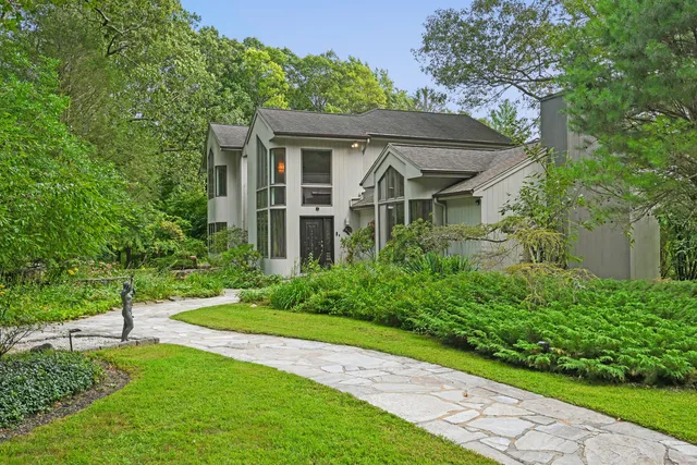 a backyard of a house with plants and large trees