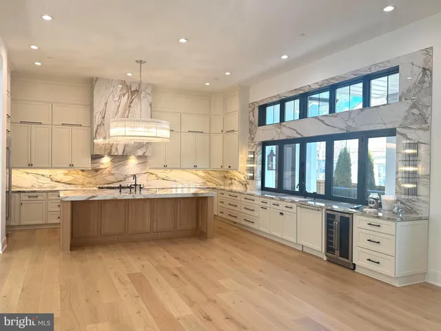 a large kitchen with kitchen island a stove a sink dishwasher and white cabinets with wooden floor