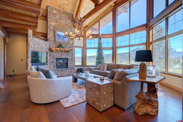a living room with fireplace furniture large windows and wooden floor