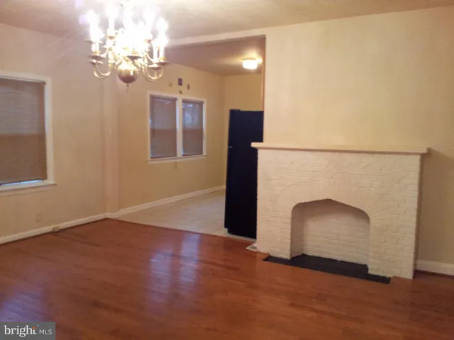 an empty room with wooden floor chandelier fan and windows