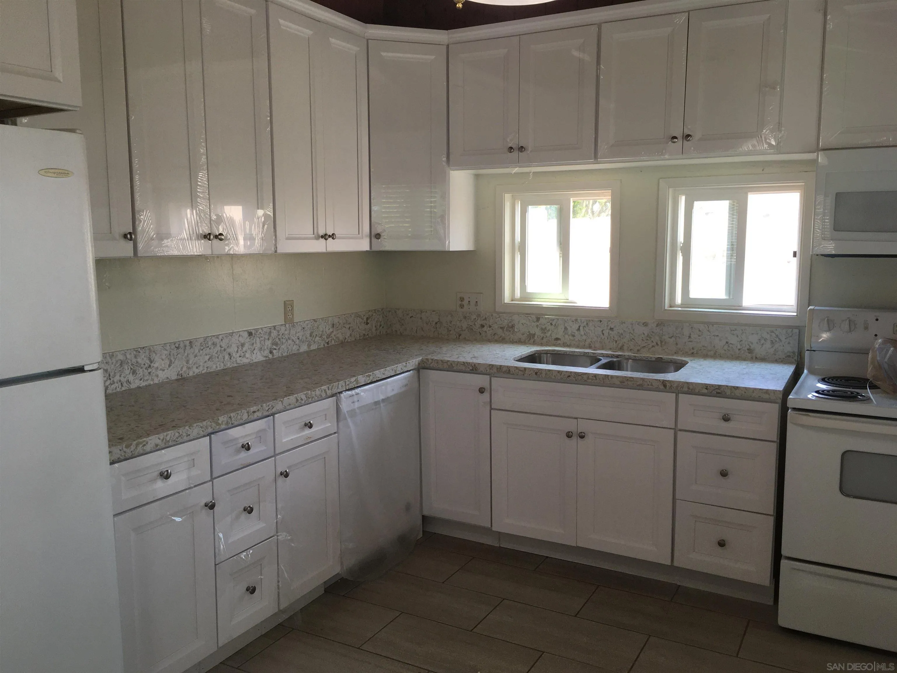 14631 Twin Peaks Road Poway, CA 92064 - Photo 3 of 12 a kitchen with granite countertop white cabinets and white appliances