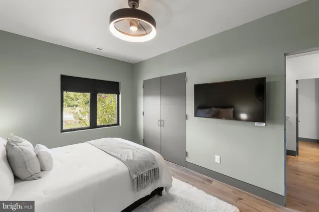 a bedroom with a bed and a flat tv screen on dresser