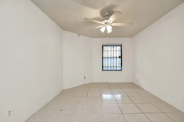 an empty room with windows and fan