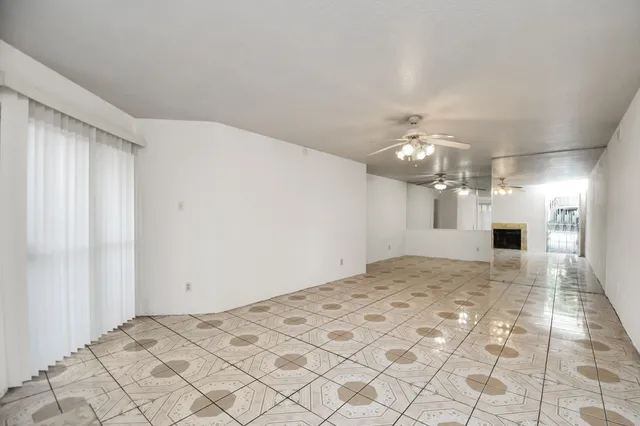 a view of a livingroom with a chandelier fan and kitchen area