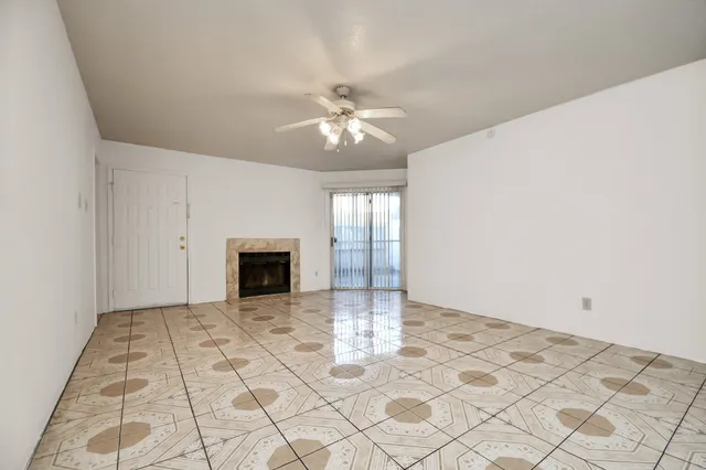 a view of an empty room with window and chandelier fan