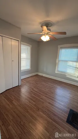 a view of empty room with wooden floor and fan