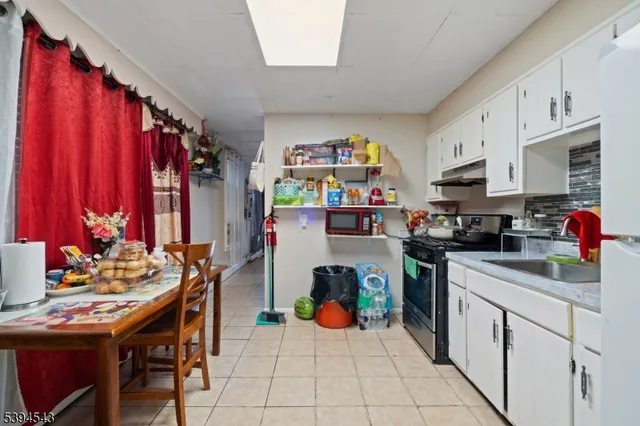 a kitchen with stainless steel appliances granite countertop a dining table chairs sink and cabinets