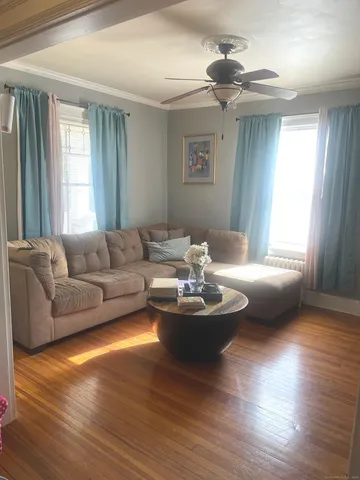 a living room with couches and a dining table with wooden floor
