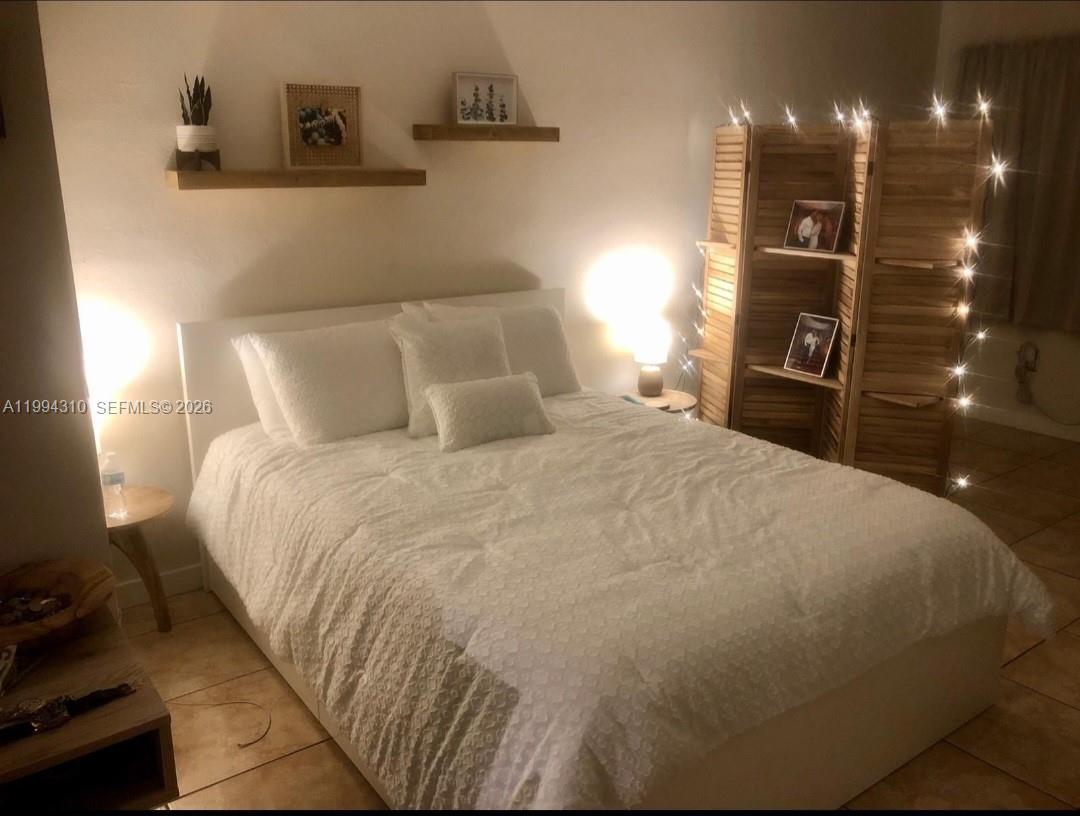 620 76th Street, Unit 11 Miami Beach, FL 33141 - Photo 12 of 14 a large bed sitting in a bedroom and next to a lamp