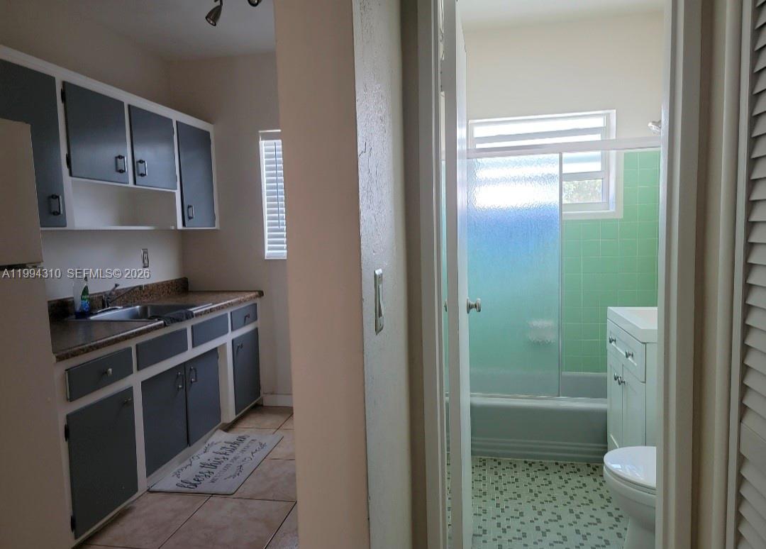 620 76th Street, Unit 11 Miami Beach, FL 33141 - Photo 7 of 14 a bathroom with a granite countertop sink a toilet and shower