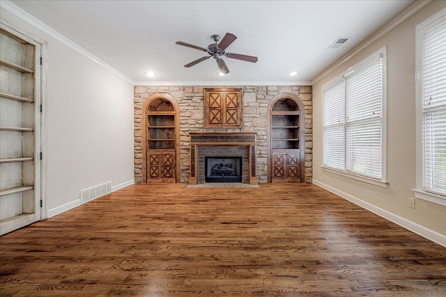 4597 Whisper Spring Drive Collierville, TN 38017 - Photo 17 of 40 Unfurnished living room with built in features, crown molding, wood finished floors, a fireplace, and ceiling fan