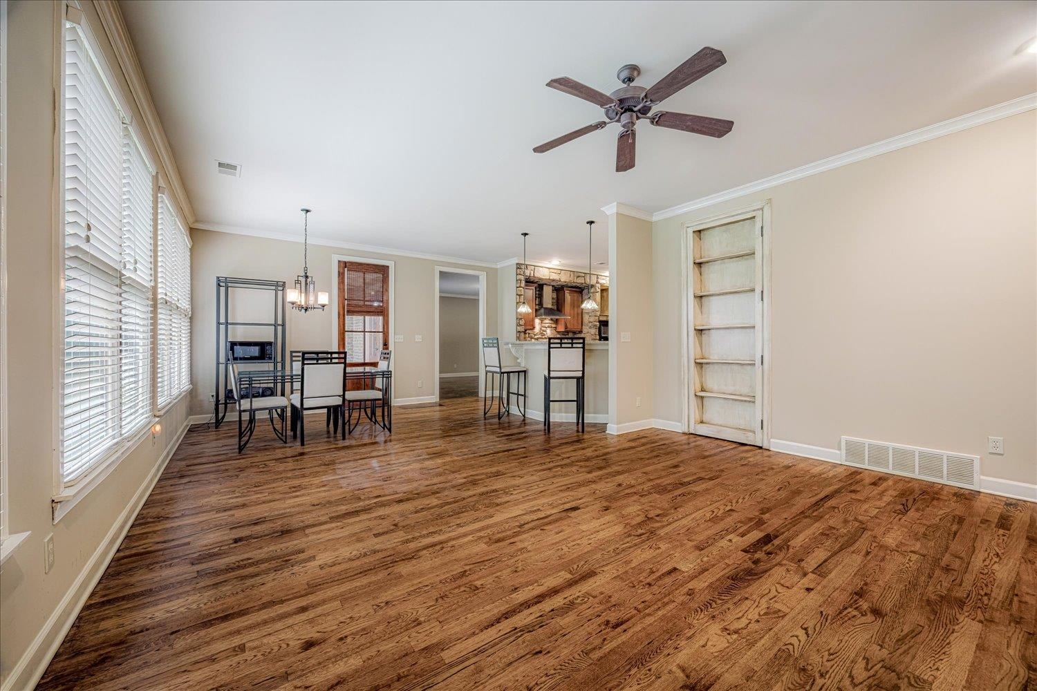 4597 Whisper Spring Drive Collierville, TN 38017 - Photo 18 of 40 Living area with crown molding, a chandelier, dark wood-type flooring, built in features, and ceiling fan