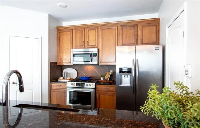 a kitchen with stainless steel appliances a refrigerator a stove a sink and a window