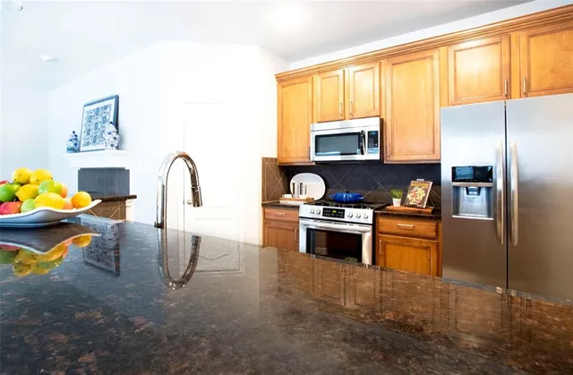 a kitchen with stainless steel appliances kitchen island granite countertop a refrigerator stove top oven and sink