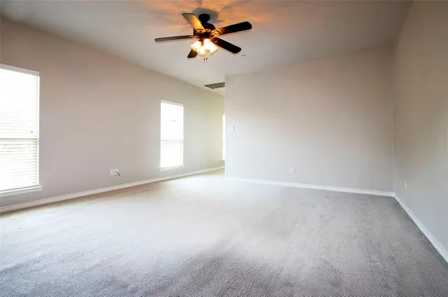 an empty room with windows and fan