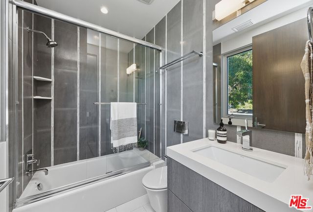 a bathroom with a bathtub shower sink vanity and toilet