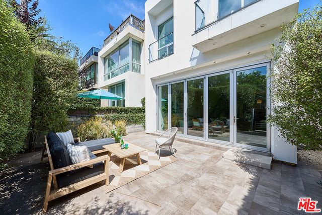 a view of a patio with a table and chairs and floor to ceiling window and tree