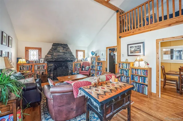 a living room with furniture a bookshelf and kitchen view