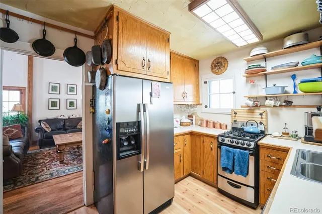 a kitchen with stainless steel appliances granite countertop a refrigerator a stove and a sink with wooden floor