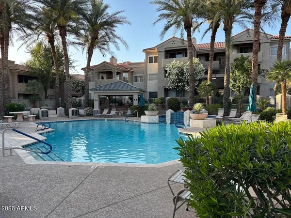 a view of a swimming pool with a table and chairs under palm trees