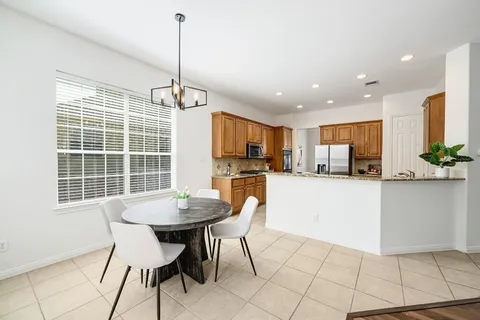 a kitchen with stainless steel appliances kitchen island granite countertop a refrigerator a stove a kitchen island with a dining table and chairs