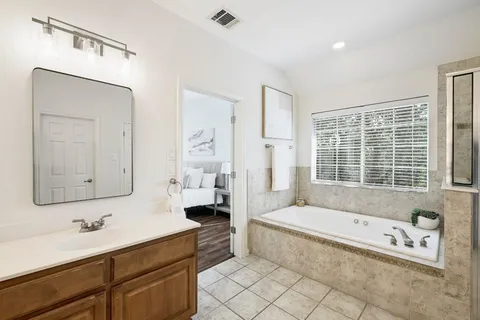 a spacious bathroom with a tub sink and mirror