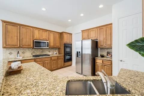 a kitchen with stainless steel appliances granite countertop a refrigerator sink and stove