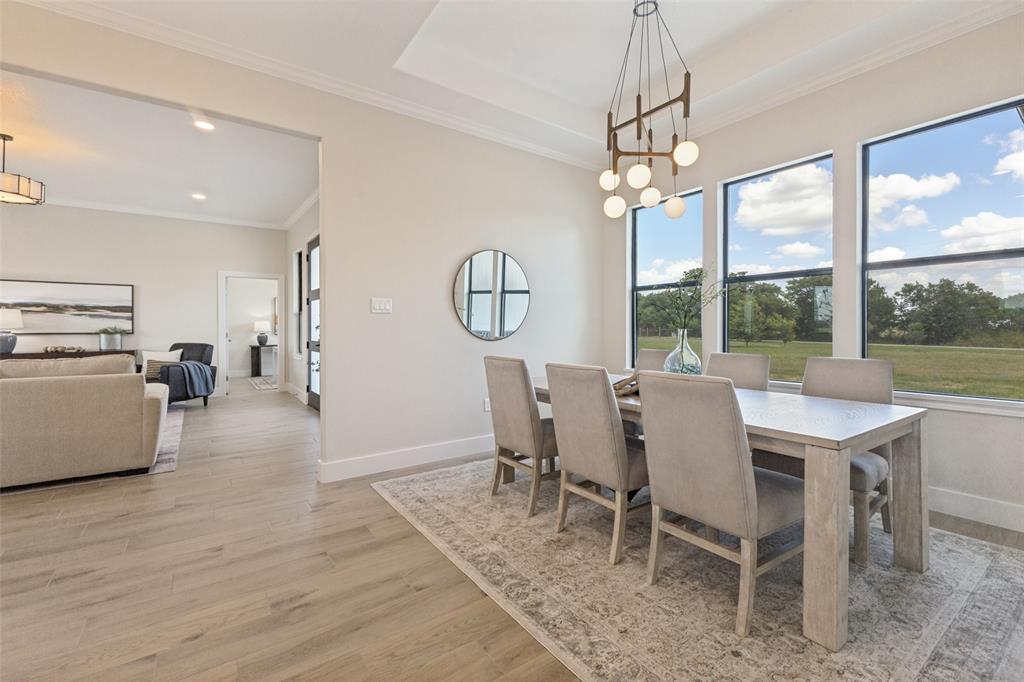 3150 Crisp Road Ennis, TX 75119 - Photo 12 of 30 Dining area featuring large windows, a contemporary chandelier, crown molding, and wood-finish flooring