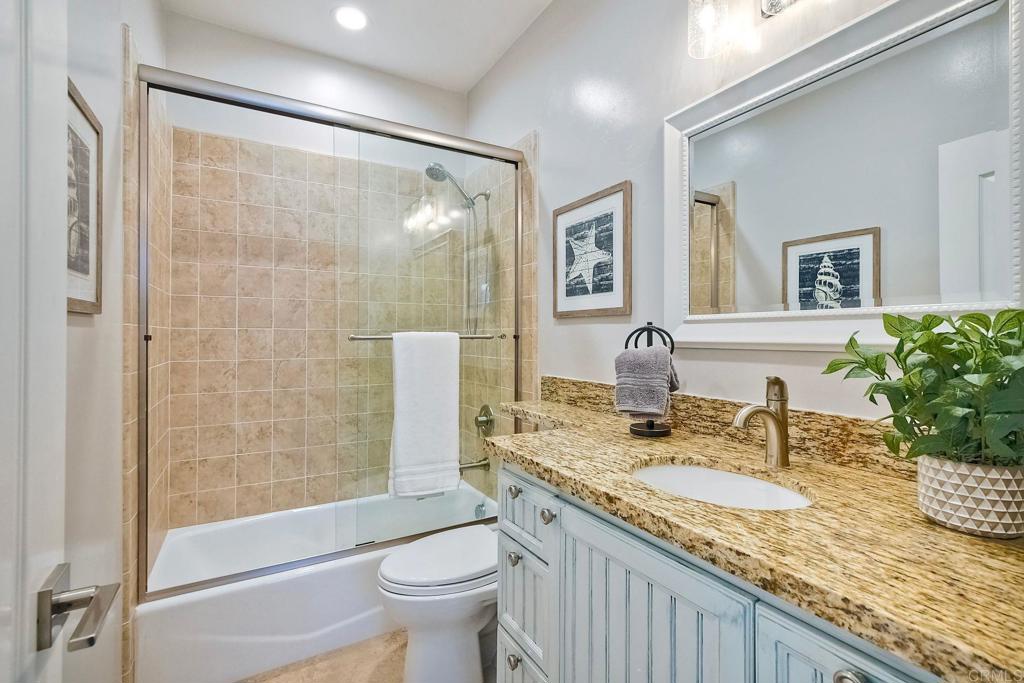 2559 Fire Mountain Drive Oceanside, CA 92054 - Photo 39 of 43 a bathroom with a granite countertop sink a toilet a mirror and shower