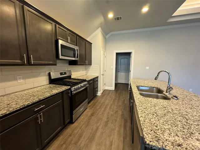 a kitchen with stainless steel appliances granite countertop a sink stove and refrigerator