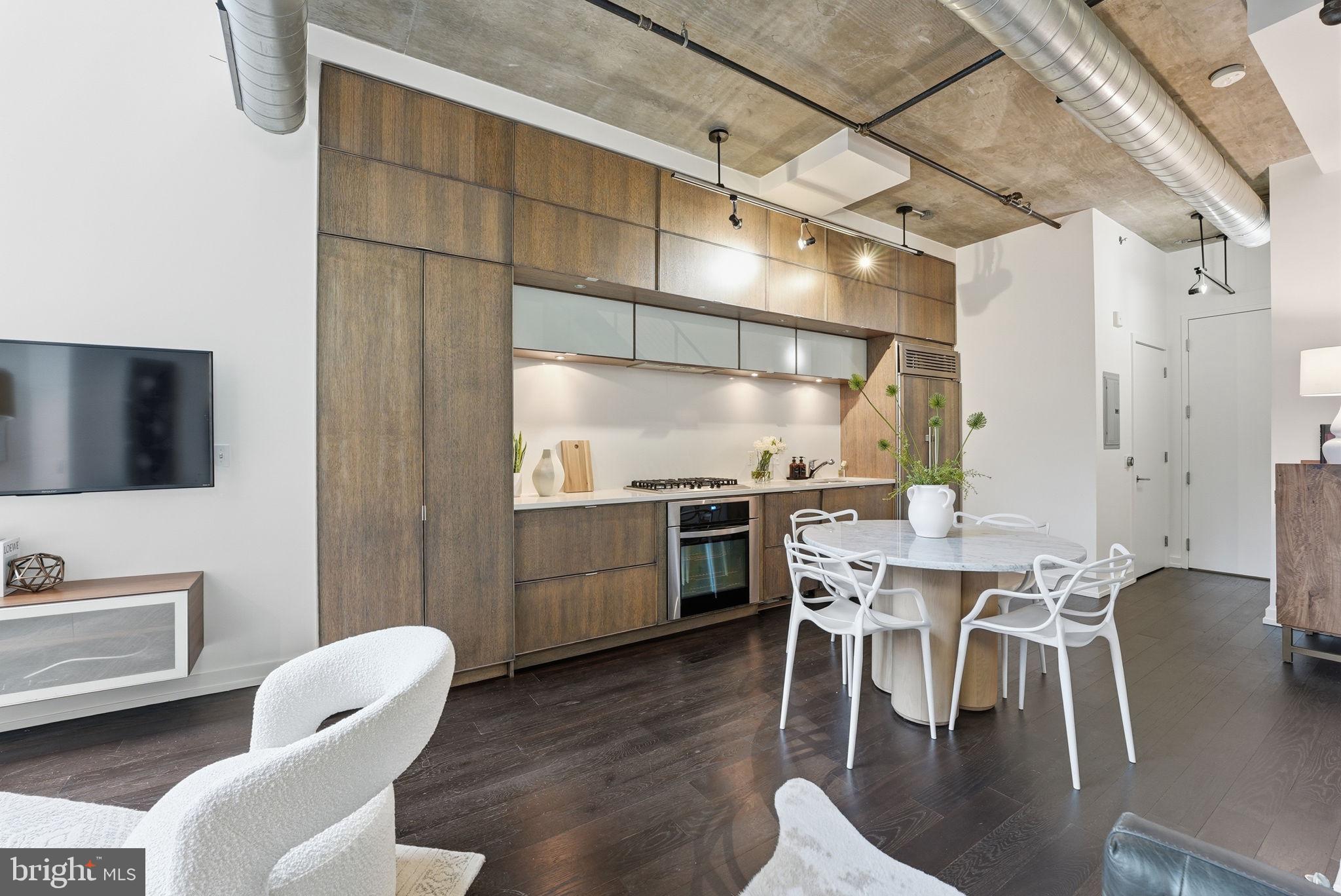 1515 15th Street Northwest, Unit 234 Washington, DC 20005 - Photo 8 of 33 a kitchen with stainless steel appliances kitchen island granite countertop a dining table chairs and a white refrigerator