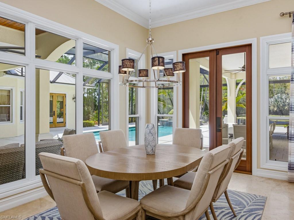 7051 Hunters Road Naples, FL 34109 - Photo 15 of 49 a view of a dining room with furniture large windows and wooden floor