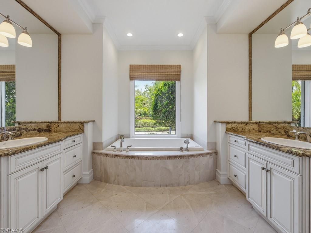 7051 Hunters Road Naples, FL 34109 - Photo 22 of 49 a spacious bathroom with a granite countertop tub sink and mirror