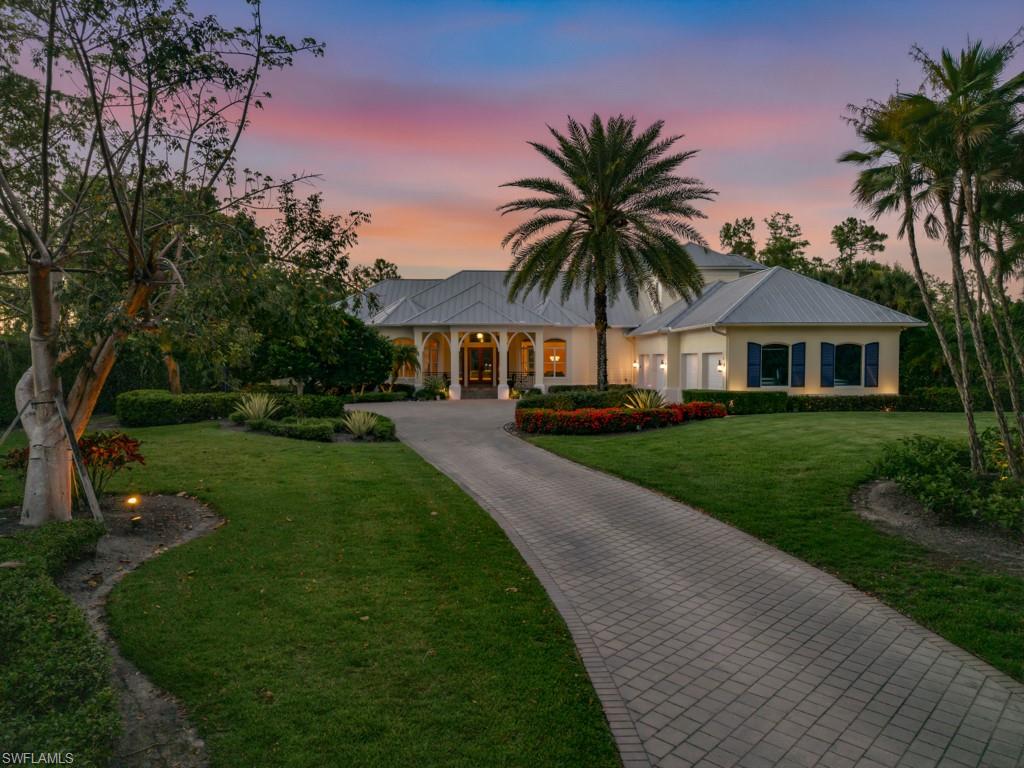 7051 Hunters Road Naples, FL 34109 - Photo 3 of 49 a front view of a house with a yard and palm tree