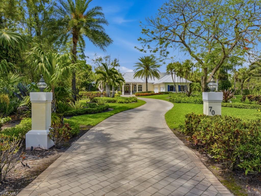 7051 Hunters Road Naples, FL 34109 - Photo 4 of 49 a front view of a house with a yard and fountain