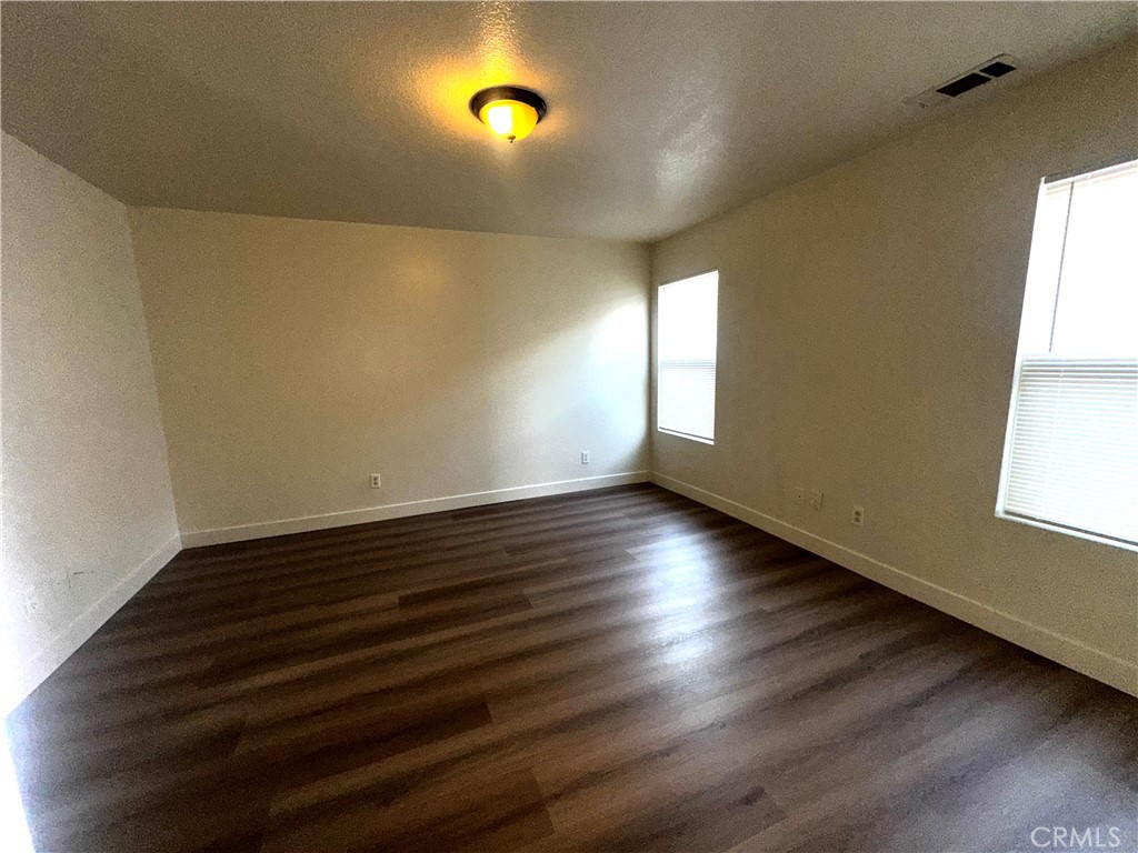 14413 Stivers Road Victorville, CA 92394 - Photo 7 of 17 an empty room with wooden floor and windows