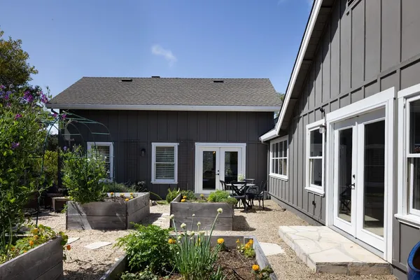 a view of a house with couches plants and large tree