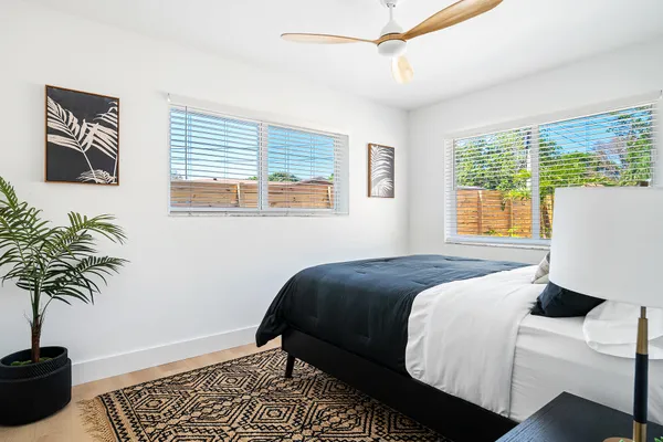 a bedroom with a bed and a window with potted plants