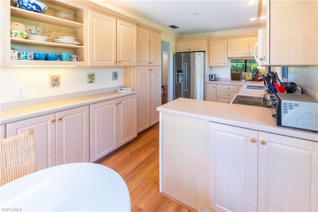 522 Beachwalk Circle Naples, FL 34108 - Photo 12 of 34 a kitchen with stainless steel appliances kitchen island wooden cabinets a sink and a refrigerator