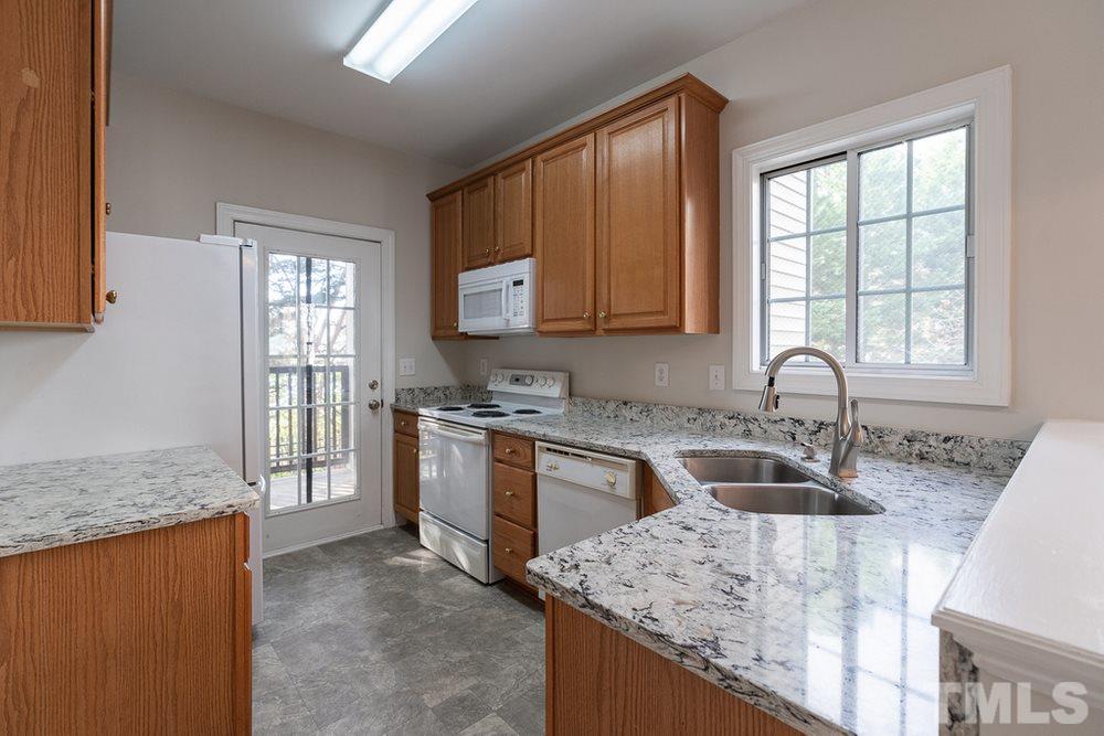 7022 Sandy Forks Road, Unit 201 Raleigh, NC 27615 - Photo 11 of 30 a kitchen with granite countertop a sink stove and cabinets