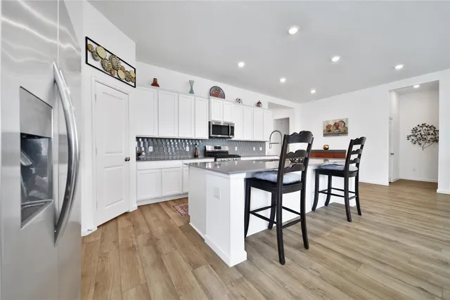 a kitchen with stainless steel appliances a refrigerator a stove top oven a sink dishwasher and a dining table with wooden floor