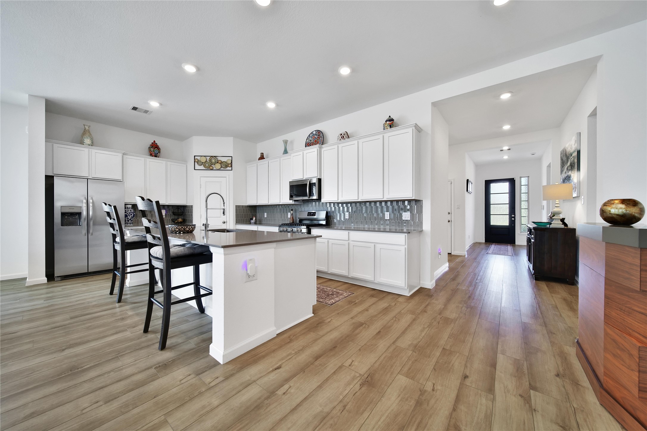 3707 Meadow Breeze Lane Rosenberg, TX 77469 - Photo 3 of 30 a kitchen with kitchen island white cabinets and stainless steel appliances