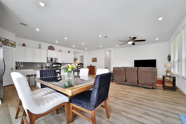 a living room with furniture and a dining table with wooden floor