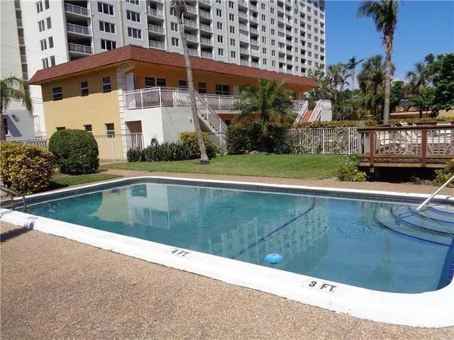 a view of swimming pool with lawn chairs and plants