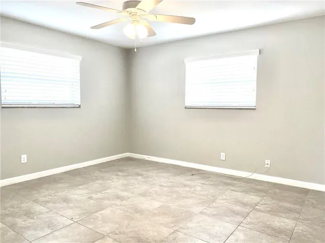 an empty room with a ceiling fan and window