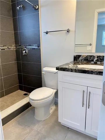 a bathroom with a granite countertop toilet a sink and a shower